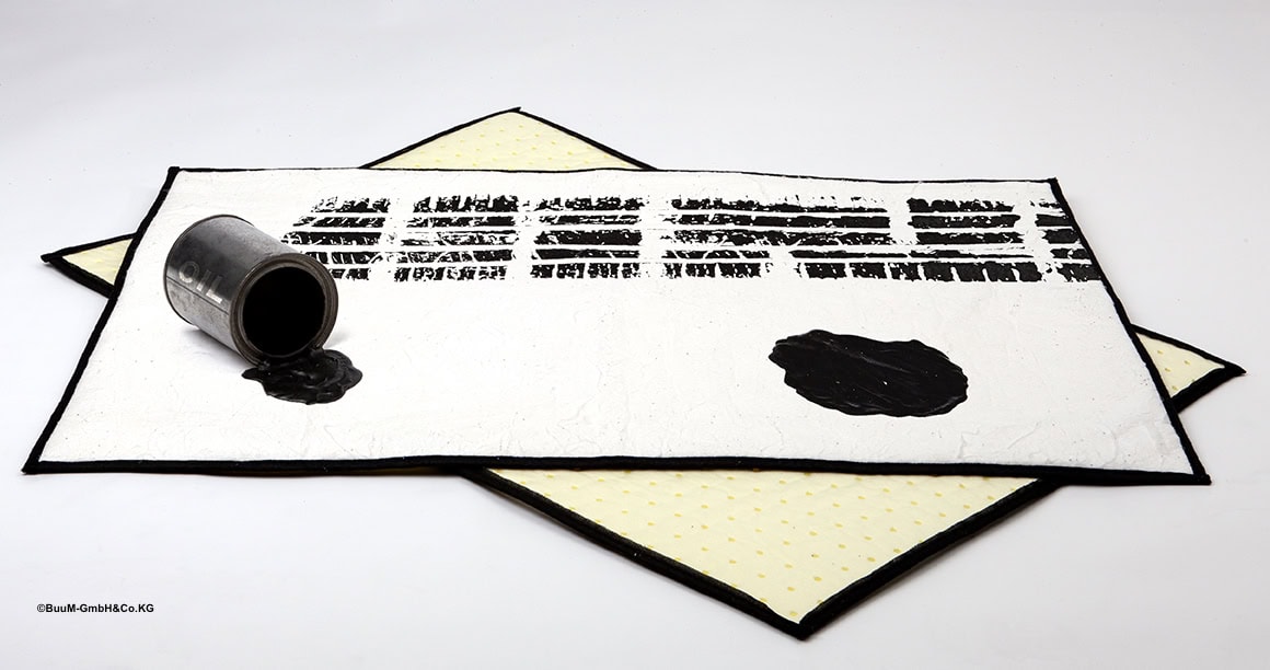 Overturned can containing black oil on a mat