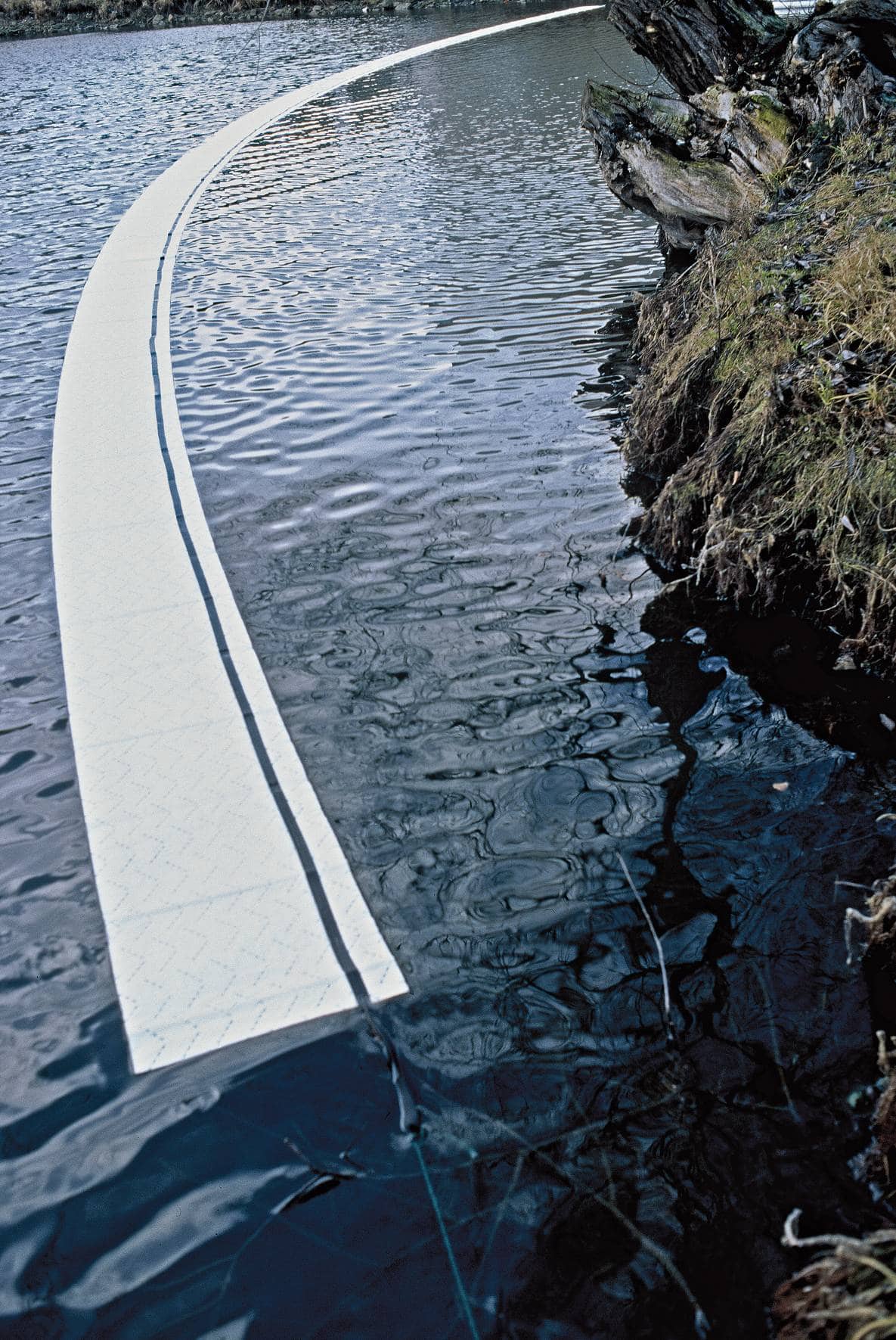 Curved floating barrier on rippling lake water